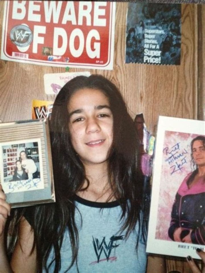 A young Bayley holding two signed photos of Bret Hart