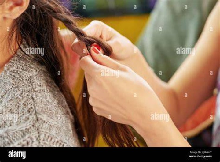 Brunette woman braiding her own hair
