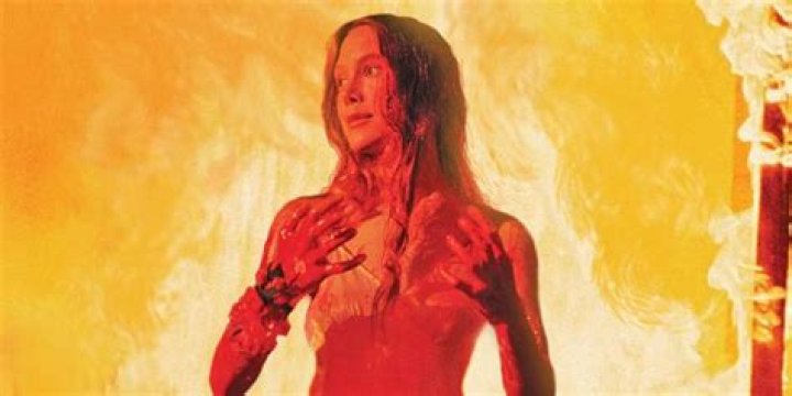 Carrie covered in blood with fire raging behind her