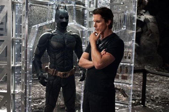 Christian Bale as Batman stands among ruins in The Dark Knight Rises