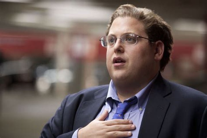 Jonah Hill as Peter Brand smiling and raising his hand in Moneyball