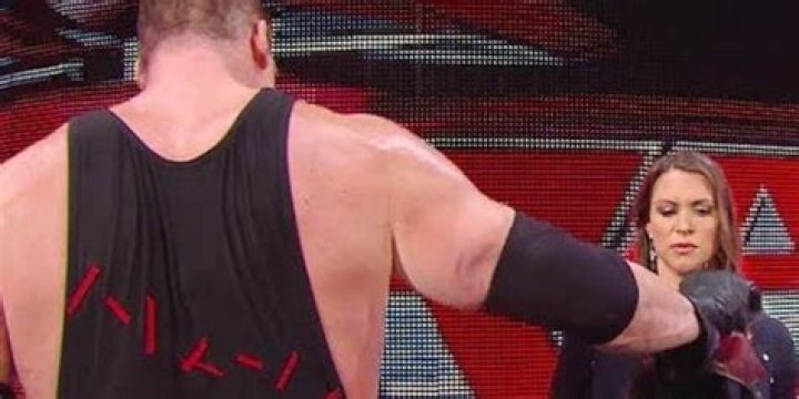 Kane handing his mask to Stephanie McMahon. 