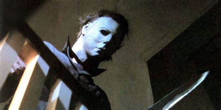 Michael Myers looking over a balcony holding a knife in Halloween 1978 
