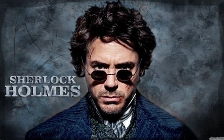 Robert Downey Jr. As Sherlock Holmes looking curious with a pipe