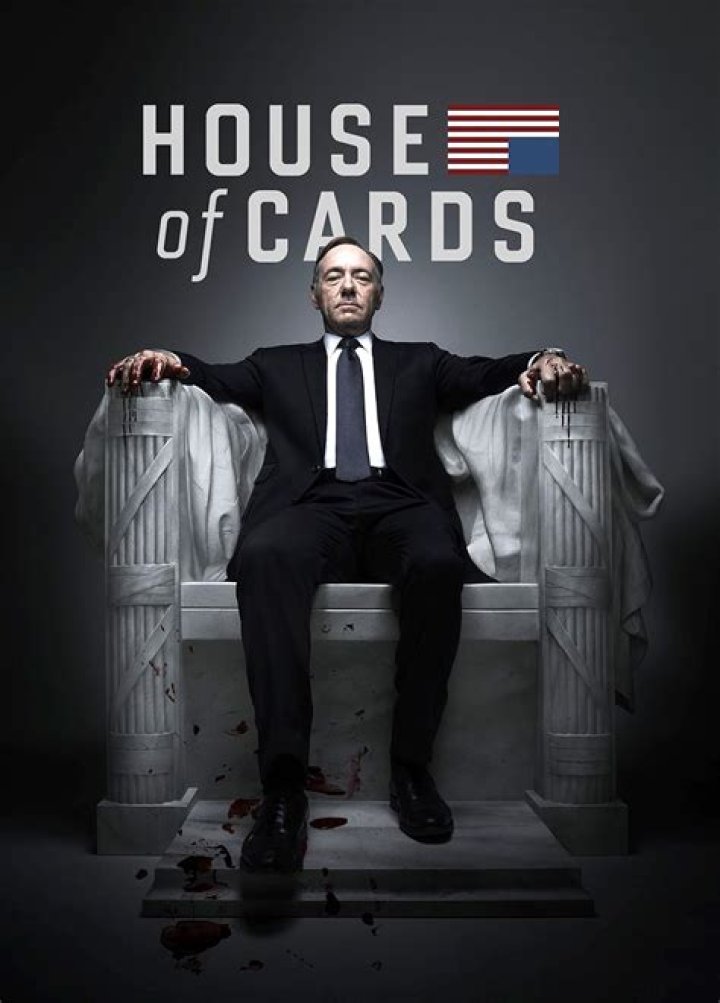 Tom from House of Cards wearing glasses and looking down at someone.