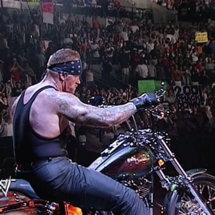 Undertaker riding a motorcycle with the Hardcore Title on his shoulder