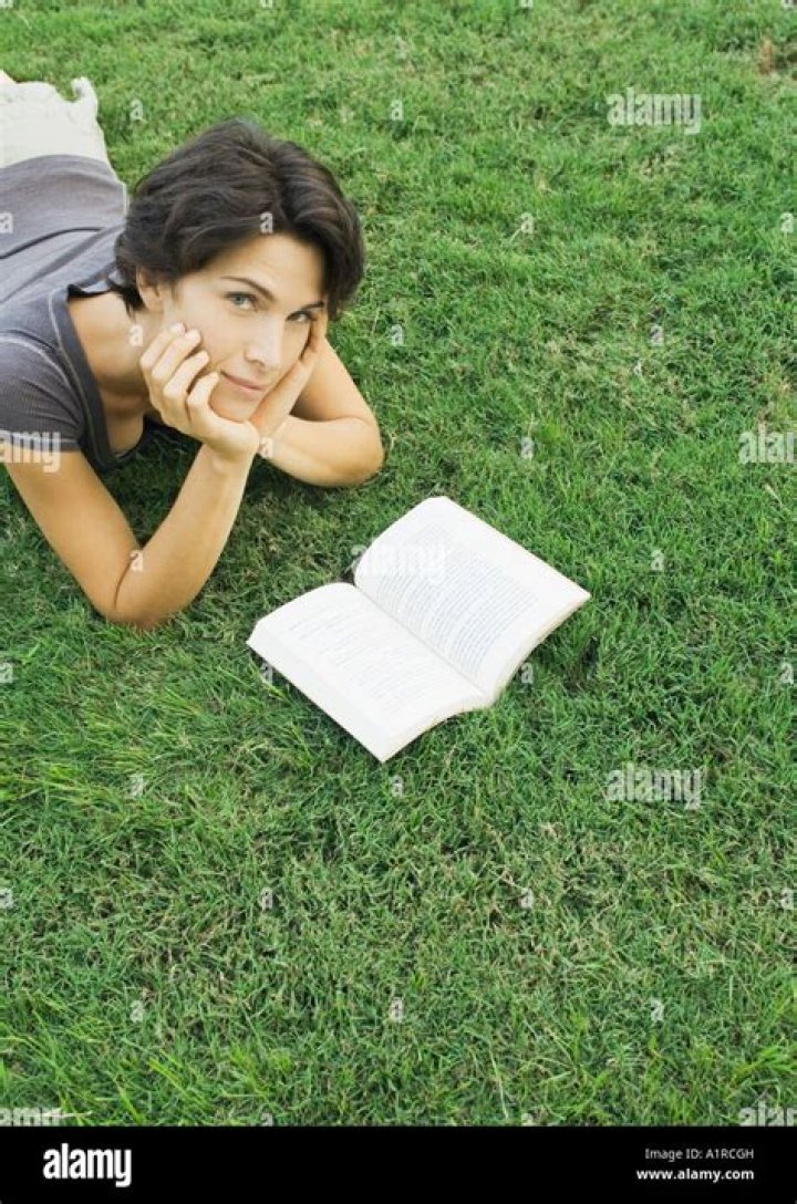 woman lying in grass reading