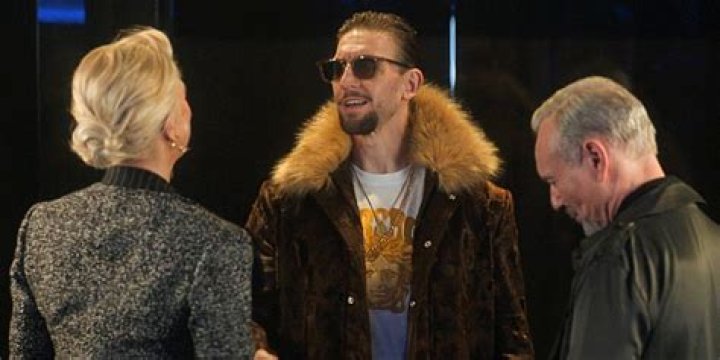 Zava (Maximilian Osinski) wearing a fur coat and sunglasses, talking to Rebecca (Hannah Waddingham) and Rupert (Anthony Head) in Ted Lasso.